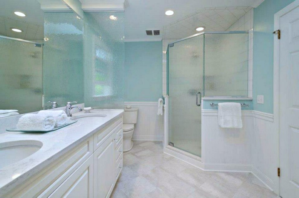 ニューヨークにあるお手頃価格の中くらいなトラディショナルスタイルのおしゃれなバスルーム (浴槽なし) (レイズドパネル扉のキャビネット、白いキャビネット、コーナー設置型シャワー、分離型トイレ、白いタイル、セラミックタイル、青い壁、セラミックタイルの床、アンダーカウンター洗面器、珪岩の洗面台、白い床、開き戸のシャワー) の写真