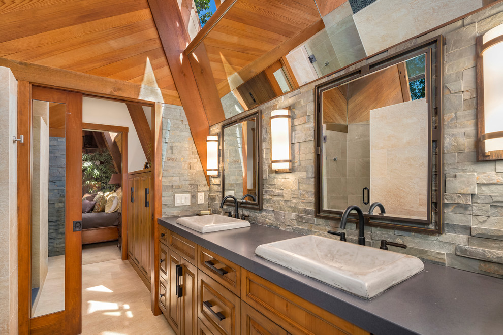 Cette image montre une petite salle de bain principale chalet en bois brun avec un placard avec porte à panneau surélevé, WC à poser, un carrelage gris, un carrelage de pierre, un mur gris, un sol en carrelage de porcelaine, une vasque et un plan de toilette en quartz modifié.