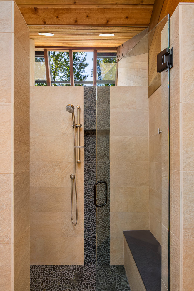 Photo of a small rustic sauna bathroom in Seattle with raised-panel cabinets, medium wood cabinets, a one-piece toilet, grey tiles, stone tiles, grey walls, pebble tile flooring, a vessel sink and engineered stone worktops.