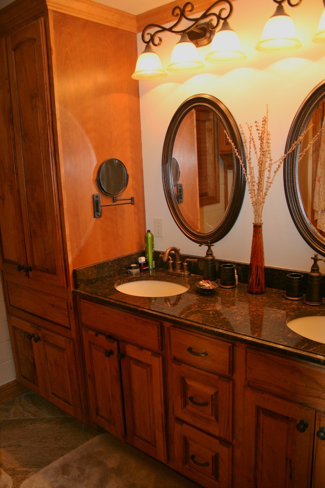 Mid-sized mountain style master brown tile and porcelain tile porcelain tile doorless shower photo in New Orleans with raised-panel cabinets, medium tone wood cabinets, a one-piece toilet, white walls, an undermount sink and granite countertops