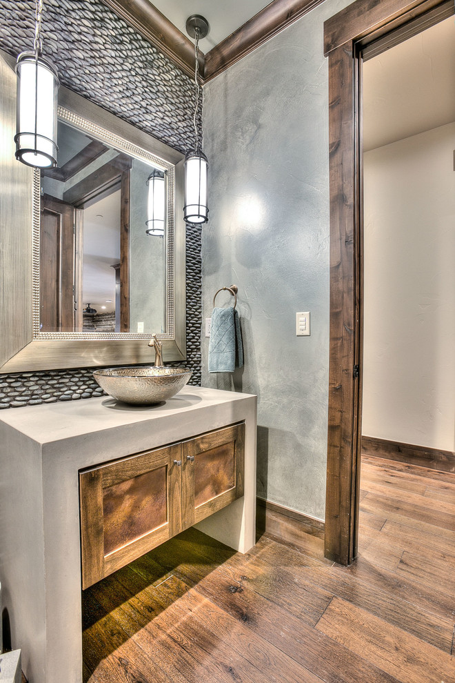 This is an example of a medium sized rustic shower room bathroom in Denver with shaker cabinets, medium wood cabinets, a two-piece toilet, grey tiles, pebble tiles, grey walls, medium hardwood flooring, a vessel sink and concrete worktops.