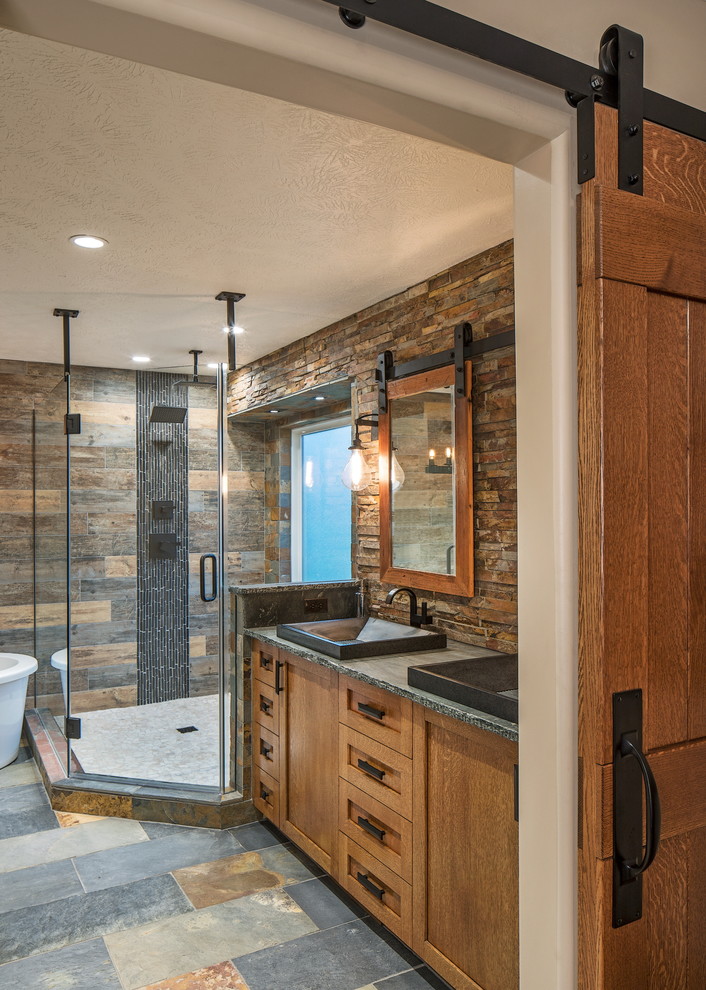 Пример оригинального дизайна: главная ванная комната в стиле рустика с фасадами в стиле шейкер, фасадами цвета дерева среднего тона, отдельно стоящей ванной, открытым душем, коричневой плиткой, каменной плиткой и столешницей из талькохлорита