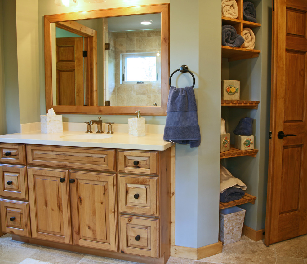 Photo of a rustic bathroom in Milwaukee with an integrated sink, raised-panel cabinets, medium wood cabinets, solid surface worktops, an alcove shower, beige tiles and green walls.
