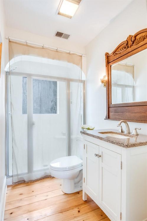 Foto de cuarto de baño rural de tamaño medio con armarios con paneles empotrados, puertas de armario blancas, paredes blancas y suelo de madera clara