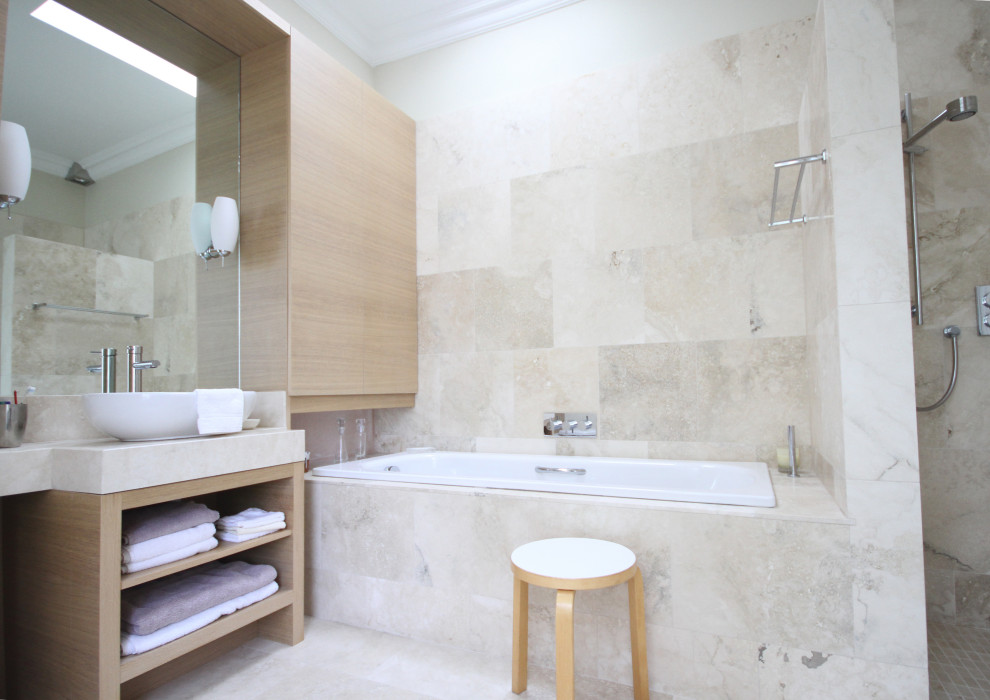 Mid-sized beige tile and limestone tile limestone floor, beige floor, single-sink and tray ceiling bathroom photo in Dublin with flat-panel cabinets, beige cabinets, a wall-mount toilet, a vessel sink, limestone countertops, a hinged shower door, beige countertops and a built-in vanity