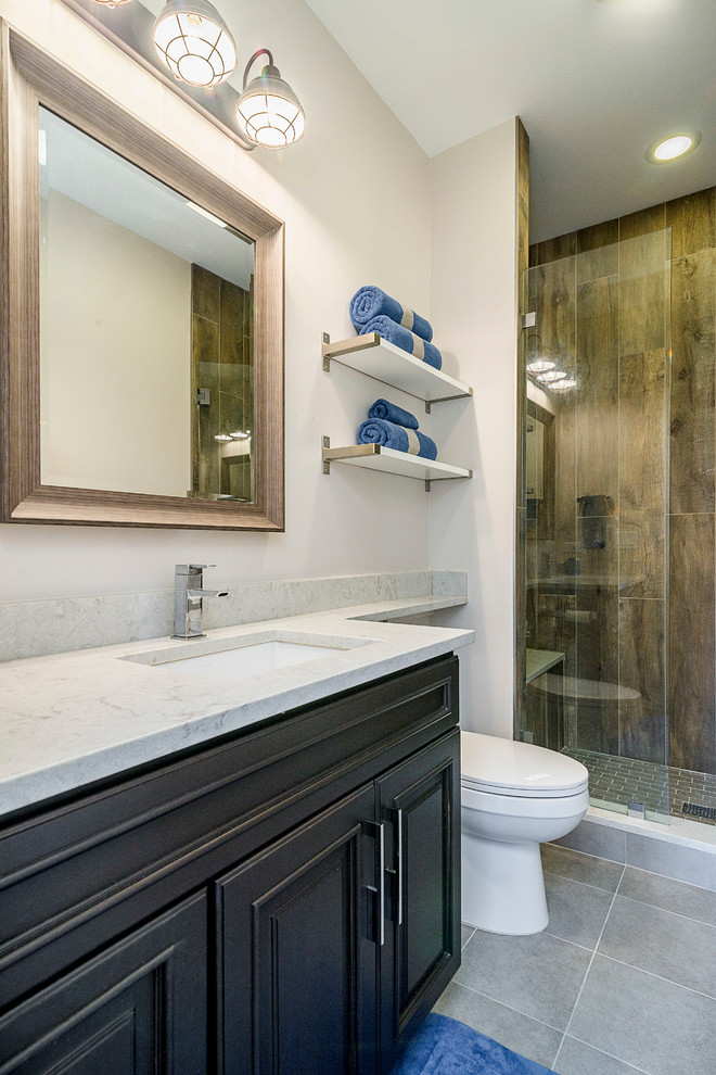 Inspiration for a mid-sized transitional 3/4 gray tile and porcelain tile ceramic tile alcove shower remodel in Chicago with raised-panel cabinets, dark wood cabinets, a two-piece toilet, beige walls, an undermount sink and quartz countertops