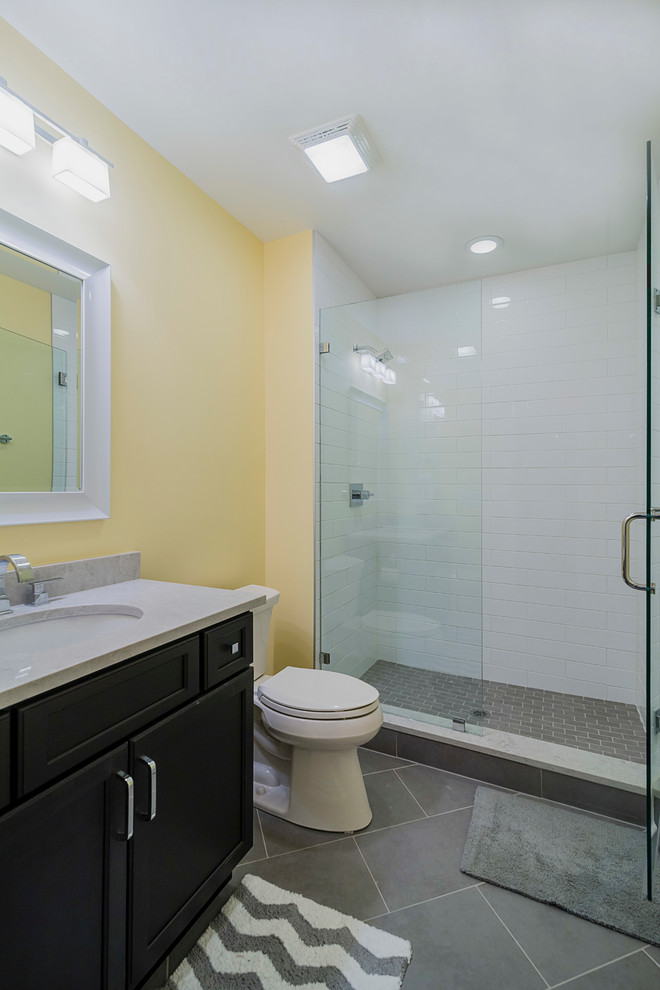 На фото: ванная комната среднего размера в стиле неоклассика (современная классика) с темными деревянными фасадами, душем в нише, раздельным унитазом, серой плиткой, керамогранитной плиткой, желтыми стенами, полом из керамогранита, врезной раковиной, фасадами с утопленной филенкой, душевой кабиной и мраморной столешницей