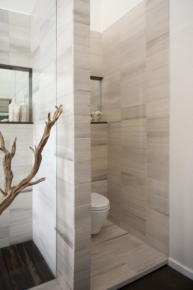 This is an example of a large rustic ensuite bathroom in Denver with flat-panel cabinets, medium wood cabinets, a freestanding bath, a built-in shower, a wall mounted toilet, white tiles, stone tiles, white walls, dark hardwood flooring, a built-in sink, brown floors, an open shower and white worktops.