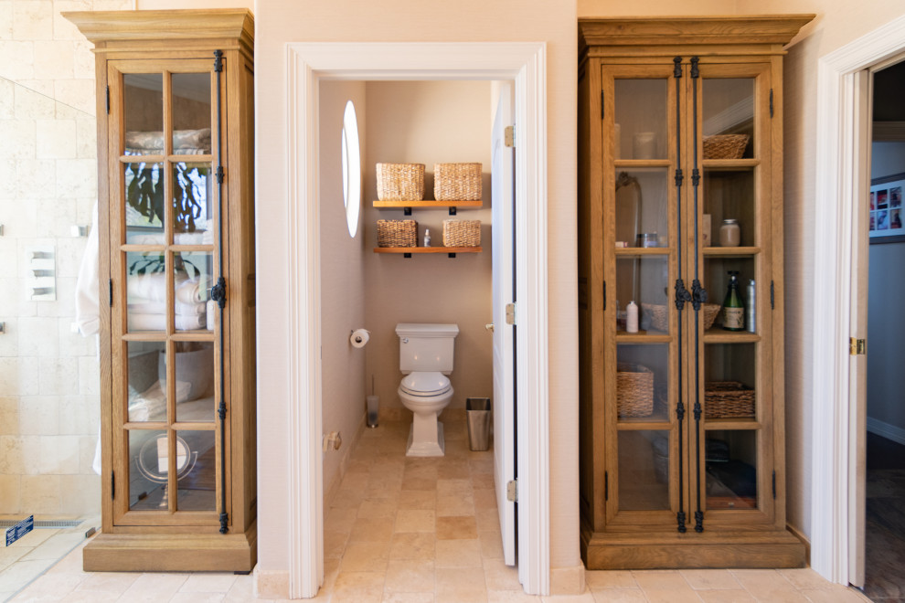 Idée de décoration pour une grande salle de bain principale méditerranéenne en bois vieilli avec un placard sans porte, un espace douche bain, WC séparés, un carrelage beige, du carrelage en travertin, un mur beige, un sol en travertin, une vasque, un plan de toilette en bois, un sol beige, une cabine de douche à porte battante et un plan de toilette marron.