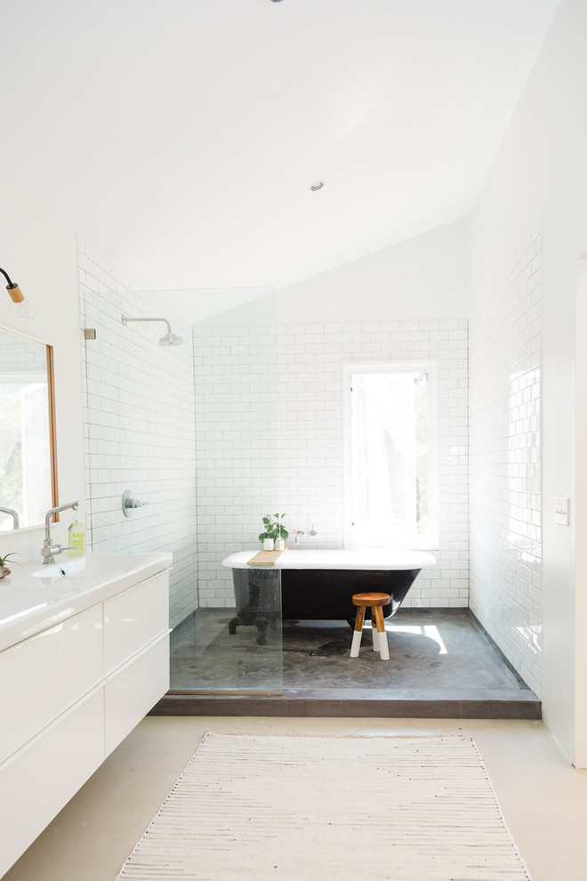 Amerikansk inredning av ett mellanstort en-suite badrum, med ett badkar med tassar, en öppen dusch, en toalettstol med hel cisternkåpa, vit kakel, tunnelbanekakel och betonggolv