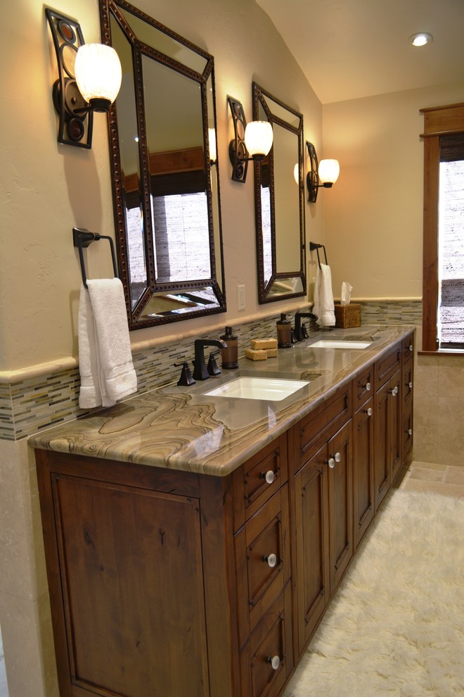Exempel på ett stort rustikt en-suite badrum, med ett undermonterad handfat, luckor med infälld panel, skåp i mörkt trä, ett undermonterat badkar, flerfärgad kakel, stickkakel, beige väggar, travertin golv, laminatbänkskiva och beiget golv