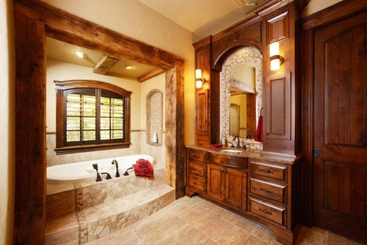 Exemple d'une grande salle de bain principale montagne en bois foncé avec un placard avec porte à panneau surélevé, une baignoire posée, un lavabo encastré et un plan de toilette en granite.
