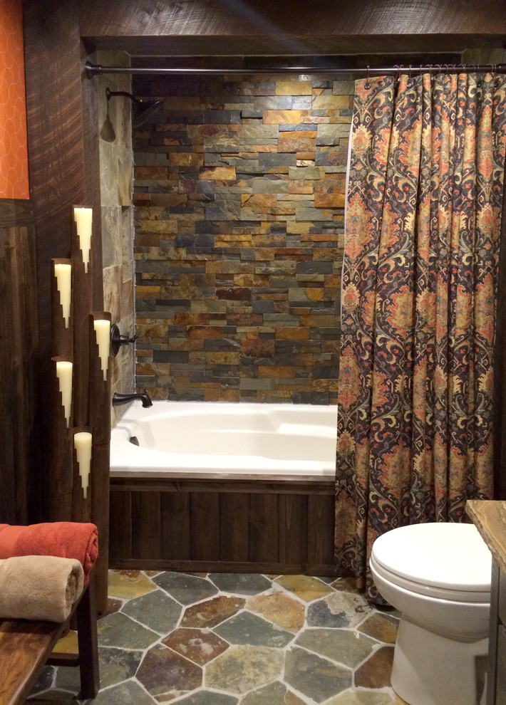 Immagine di una stanza da bagno rustica di medie dimensioni con lavabo a bacinella, top in quarzite, vasca da incasso, vasca/doccia, WC a due pezzi, pareti arancioni e consolle stile comò