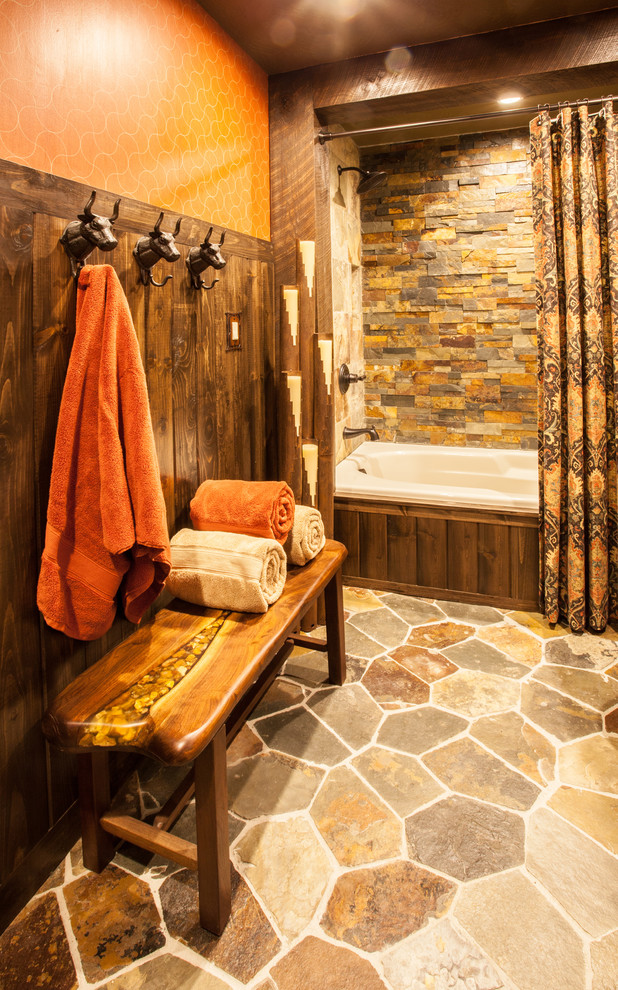 Rustik inredning av ett mellanstort badrum, med möbel-liknande, gröna skåp, ett platsbyggt badkar, en dusch/badkar-kombination, en toalettstol med separat cisternkåpa, orange väggar, ett fristående handfat och bänkskiva i kvartsit