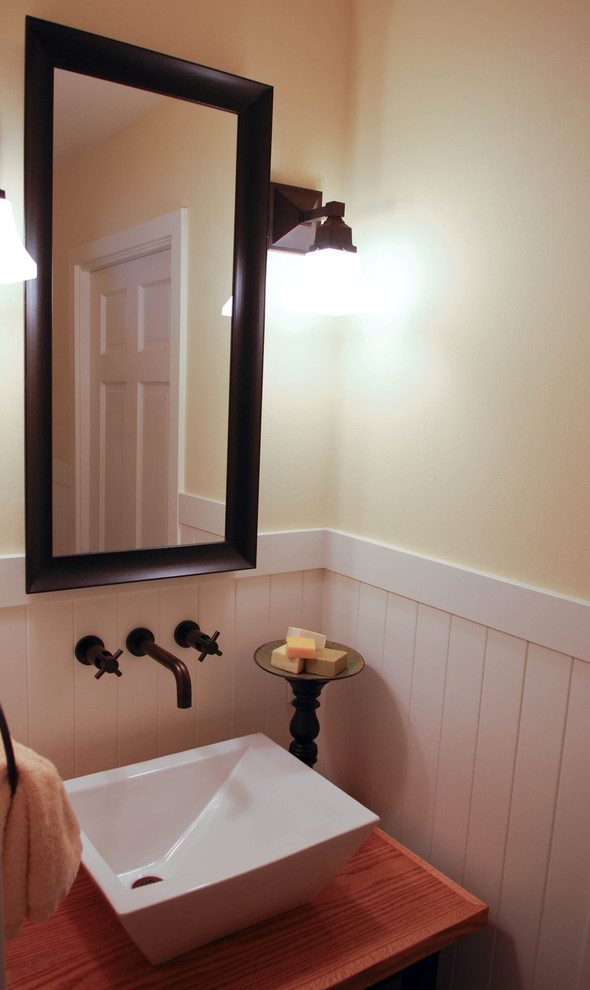 Exemple d'une petite salle d'eau nature en bois brun avec un placard sans porte, un mur jaune, une vasque et un plan de toilette en bois.