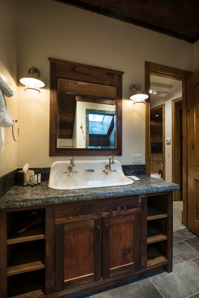 Exemple d'une salle de bain montagne en bois foncé de taille moyenne avec un placard à porte shaker, un carrelage gris, des carreaux de porcelaine, un mur beige, un sol en carrelage de porcelaine, un lavabo posé, un plan de toilette en granite, un sol gris, une cabine de douche à porte battante et un plan de toilette gris.
