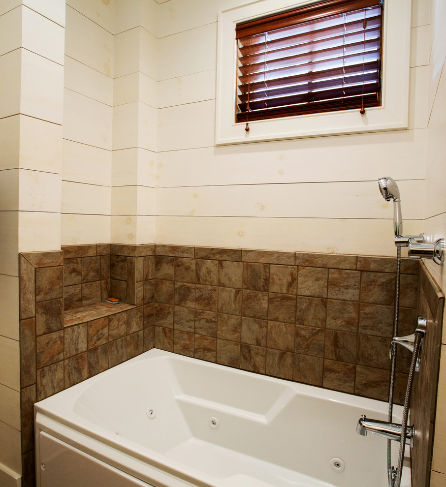 На фото: большая главная ванная комната в стиле кантри с гидромассажной ванной, коричневой плиткой, керамической плиткой и желтыми стенами с