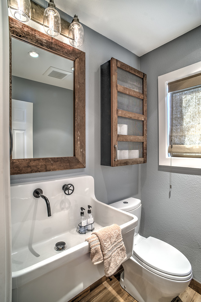 Réalisation d'une petite salle de bain chalet en bois vieilli avec un lavabo suspendu, WC séparés, des carreaux de porcelaine, un mur gris et un sol en carrelage de porcelaine.