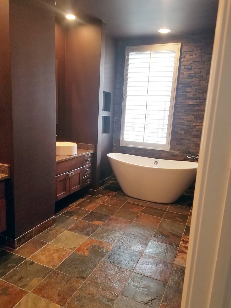 Идея дизайна: большая главная ванная комната в стиле рустика с фасадами в стиле шейкер, фасадами цвета дерева среднего тона, отдельно стоящей ванной, душем в нише, раздельным унитазом, коричневой плиткой, плиткой из сланца, коричневыми стенами, полом из сланца, настольной раковиной, столешницей из гранита, разноцветным полом и душем с распашными дверями