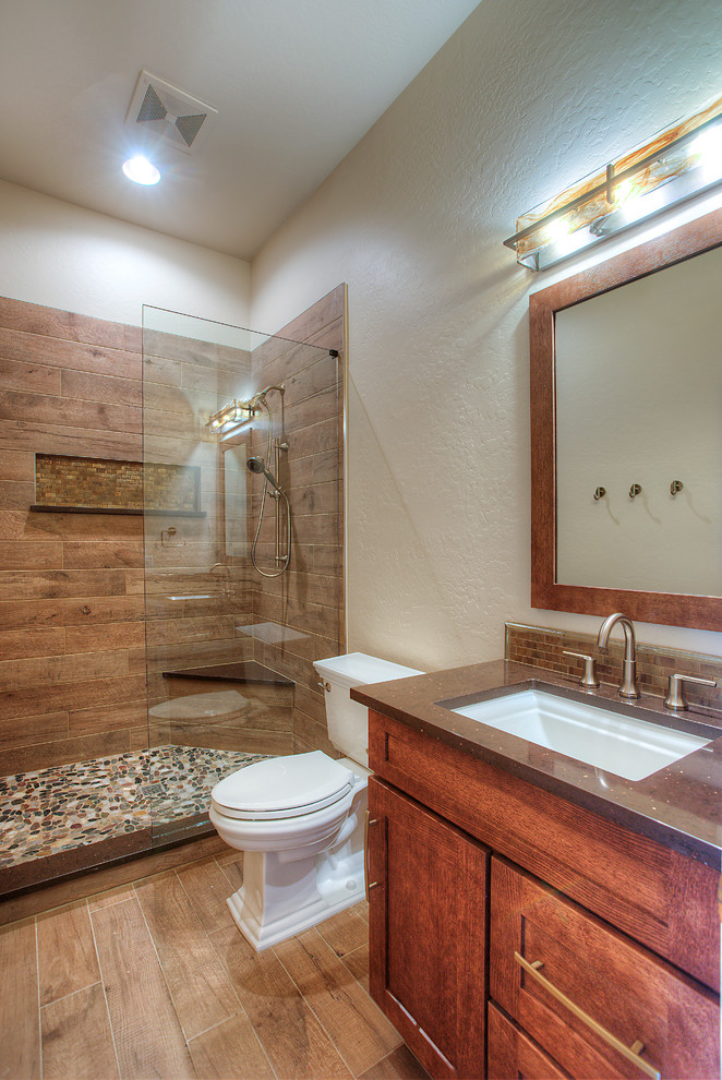 Inredning av ett rustikt mellanstort brun brunt badrum med dusch, med skåp i shakerstil, skåp i mellenmörkt trä, en dusch i en alkov, en toalettstol med separat cisternkåpa, brun kakel, keramikplattor, beige väggar, ljust trägolv, ett undermonterad handfat, bänkskiva i akrylsten, brunt golv och med dusch som är öppen