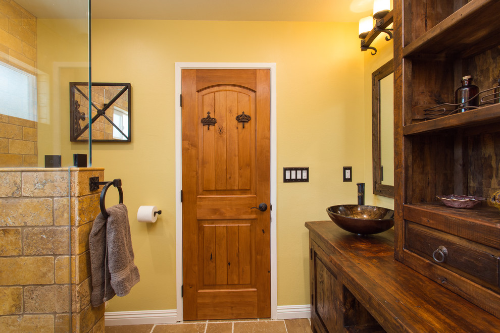 Пример оригинального дизайна: главная ванная комната среднего размера в стиле фьюжн с фасадами островного типа, искусственно-состаренными фасадами, душем без бортиков, раздельным унитазом, желтой плиткой, плиткой из травертина, бежевыми стенами, полом из травертина, настольной раковиной, столешницей из дерева, бежевым полом и душем с распашными дверями