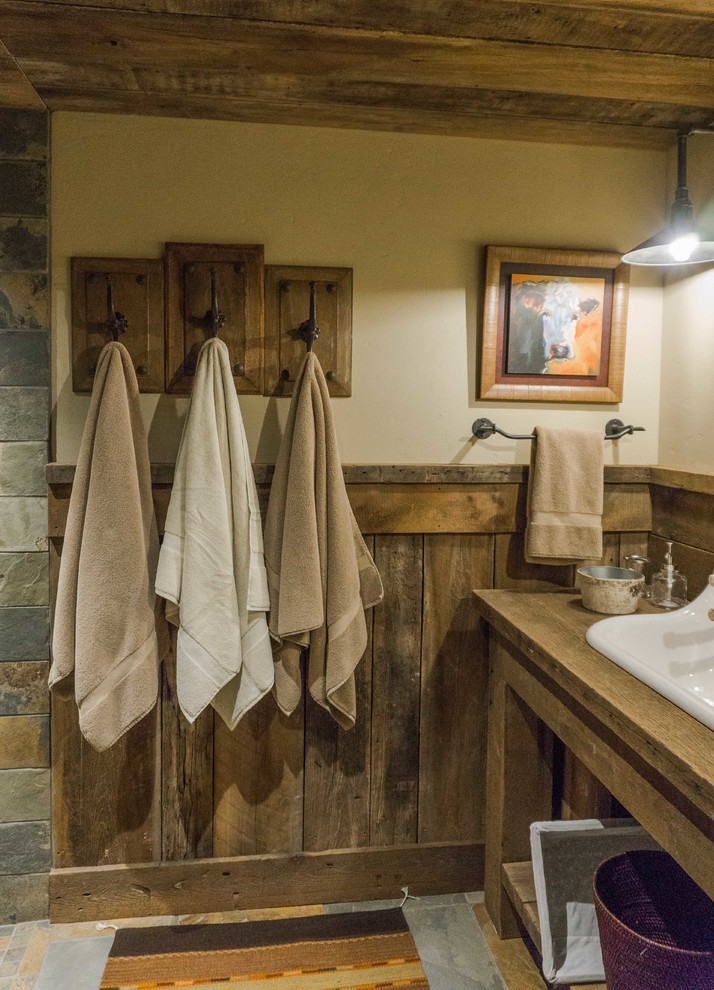 Foto på ett rustikt badrum med dusch, med en hörndusch, flerfärgad kakel, stenkakel, skiffergolv, ett avlångt handfat och träbänkskiva