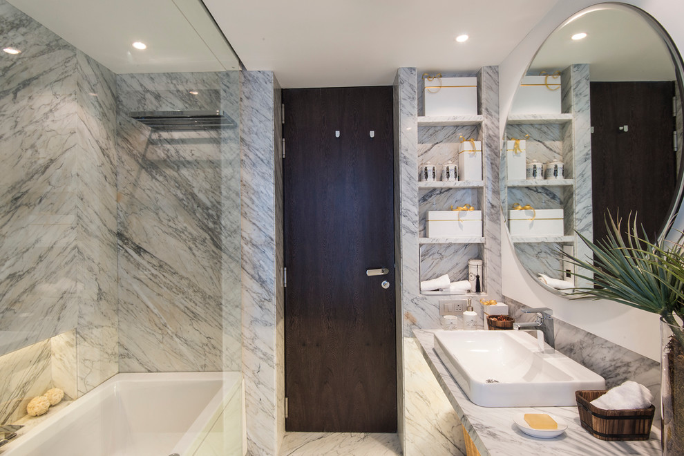 Foto di una stanza da bagno minimal con vasca ad alcova, vasca/doccia, lastra di pietra, pavimento in marmo, lavabo a bacinella e top in marmo