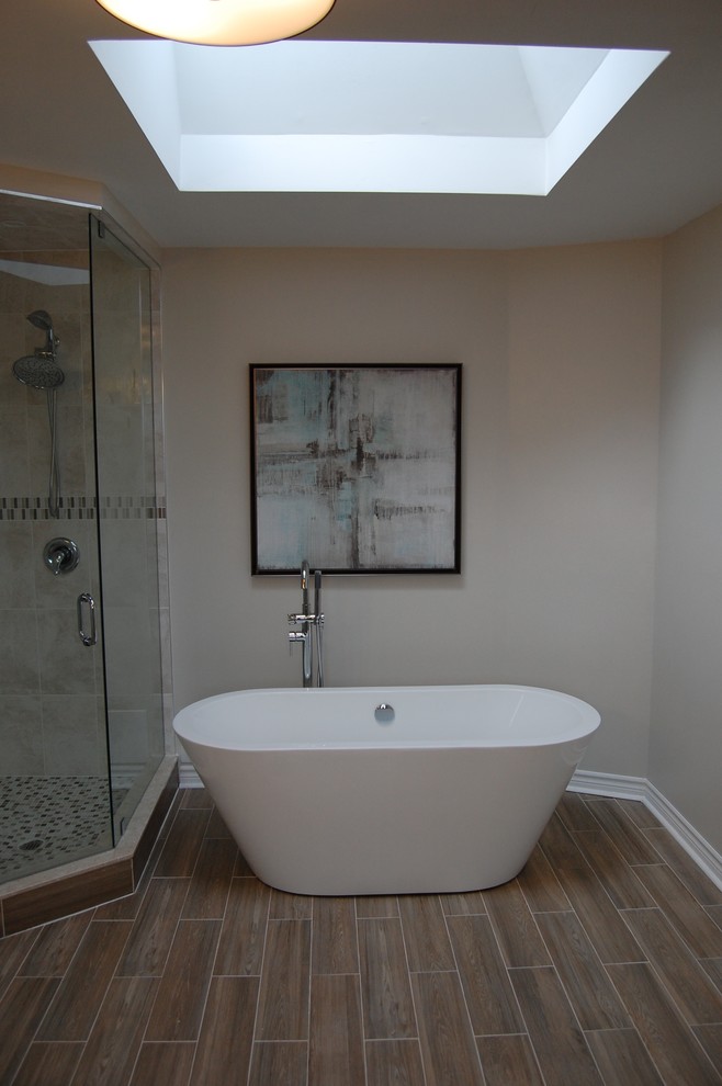 Klassisk inredning av ett stort en-suite badrum, med ett fristående badkar, en hörndusch, en toalettstol med hel cisternkåpa, flerfärgad kakel, keramikplattor, grå väggar och klinkergolv i keramik