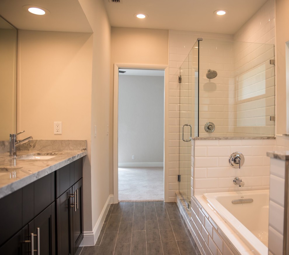 Design ideas for a medium sized classic ensuite bathroom in Columbus with shaker cabinets, dark wood cabinets, a built-in bath, a corner shower, a two-piece toilet, beige walls, a submerged sink, marble worktops, medium hardwood flooring, brown floors, a hinged door, white tiles and metro tiles.
