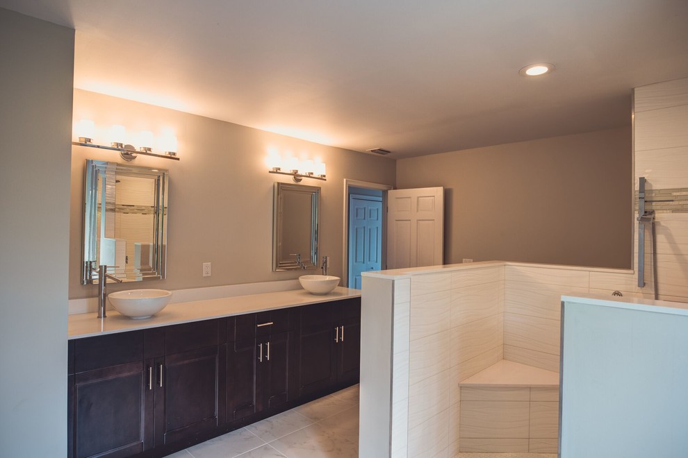 Design ideas for a large contemporary ensuite bathroom in Columbus with recessed-panel cabinets, dark wood cabinets, a built-in shower, a two-piece toilet, white tiles, ceramic tiles, beige walls, a vessel sink, tiled worktops and marble flooring.