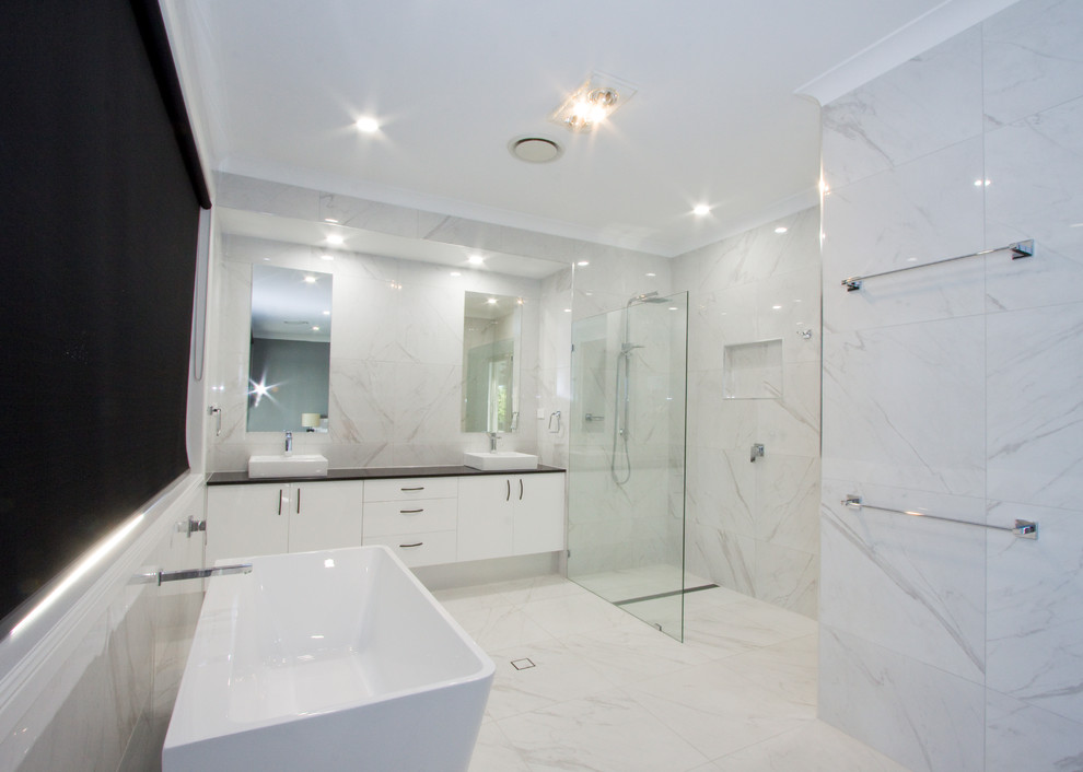 Inspiration for a large modern ensuite bathroom in Sunshine Coast with white cabinets, a freestanding bath, a walk-in shower, white tiles, porcelain tiles, white walls, porcelain flooring, granite worktops, white floors, an open shower and black worktops.
