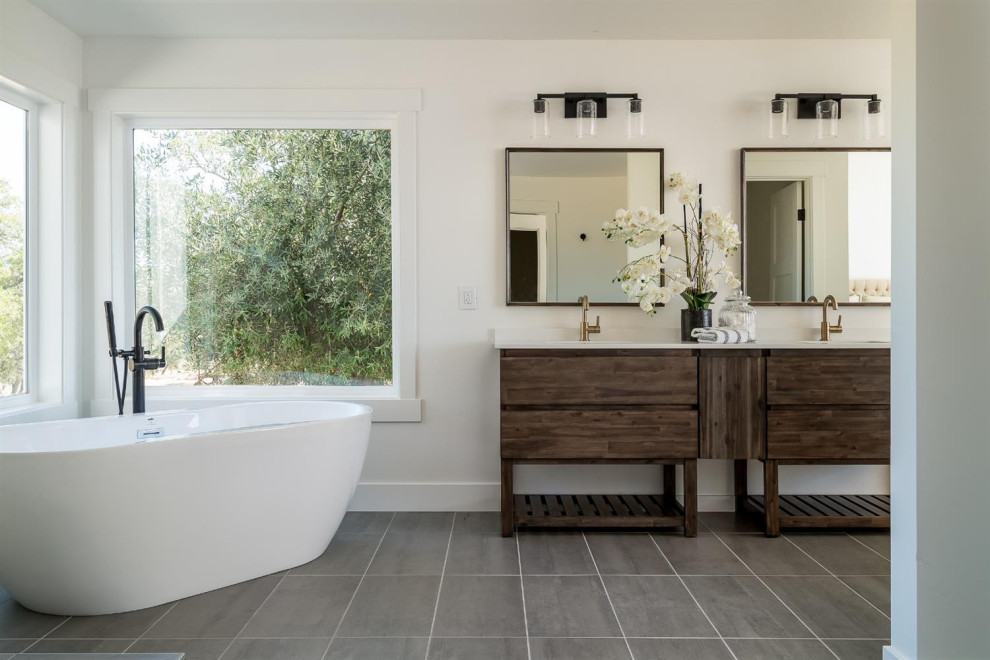 Immagine di una stanza da bagno country con ante in legno bruno, vasca freestanding, pareti bianche, pavimento grigio, top bianco e ante lisce