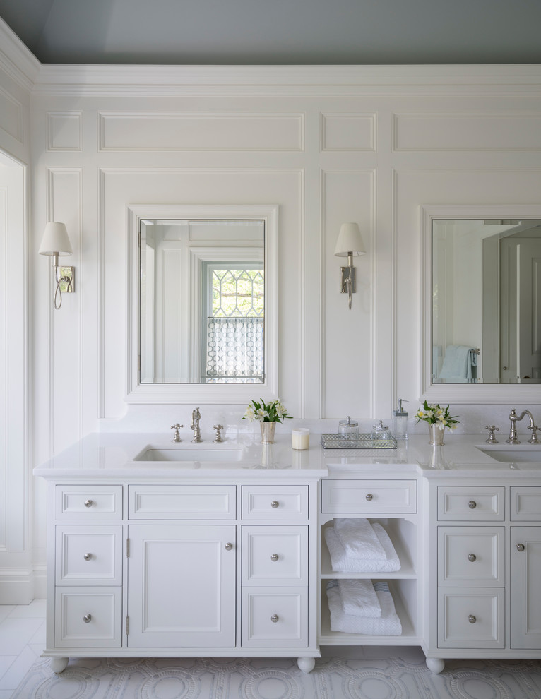 Idée de décoration pour une grande salle de bain principale tradition avec un placard avec porte à panneau encastré, des portes de placard blanches, un mur blanc, un sol en marbre, un plan de toilette en marbre et un sol blanc.