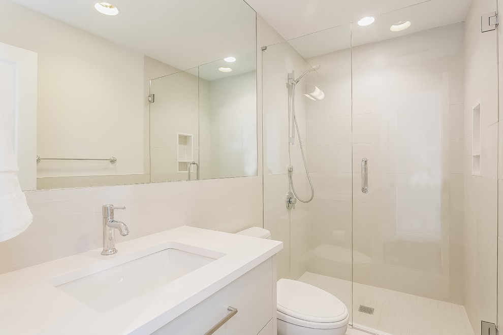 Medium sized traditional shower room bathroom in New York with flat-panel cabinets, white cabinets, an alcove shower, a two-piece toilet, white tiles, porcelain tiles, white walls, porcelain flooring, a submerged sink, solid surface worktops, white floors and a hinged door.