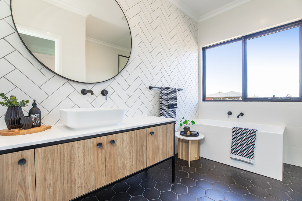 Idee per una stanza da bagno scandinava con ante lisce, ante in legno chiaro, vasca ad angolo, piastrelle bianche, pareti bianche, lavabo a bacinella, pavimento nero e top bianco