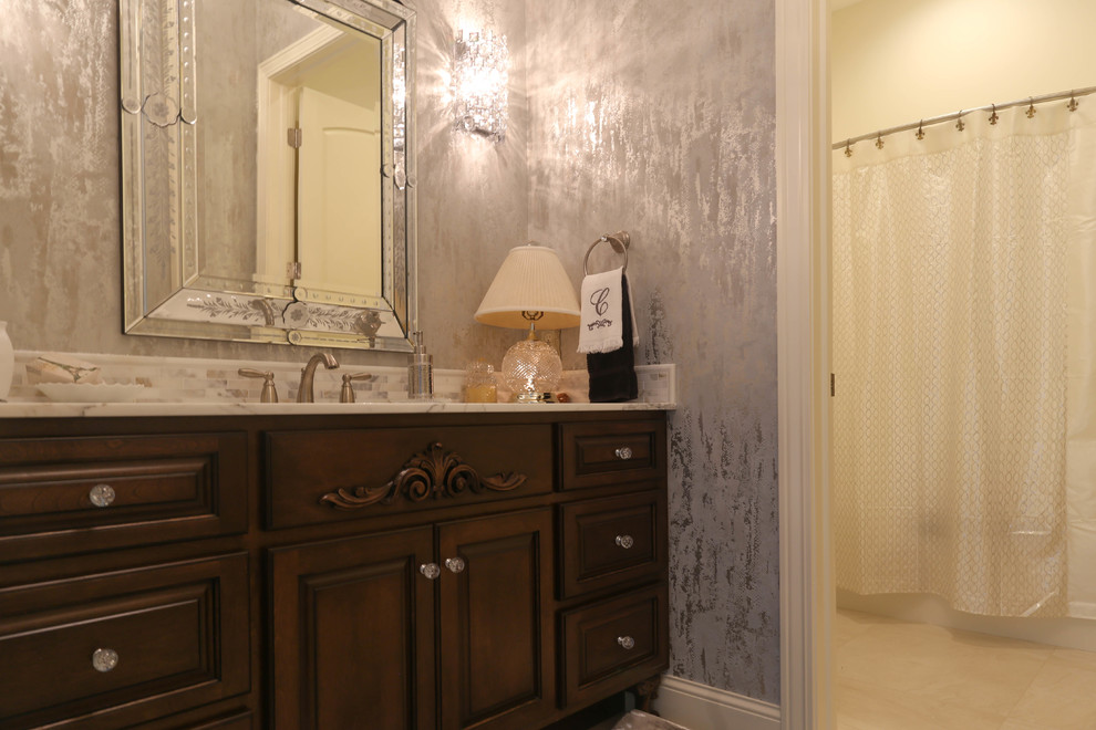 Mid-sized tuscan porcelain tile and beige floor bathroom photo in Other with raised-panel cabinets, dark wood cabinets, a two-piece toilet, gray walls, an undermount sink and granite countertops