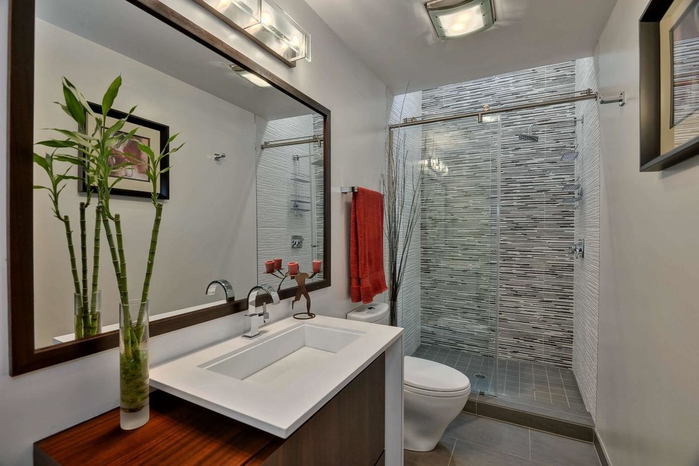 Aménagement d'une douche en alcôve moderne en bois brun avec un placard à porte plane, un plan de toilette en quartz modifié, un carrelage gris, des carreaux de porcelaine, un lavabo intégré, un mur blanc et un sol en carrelage de porcelaine.