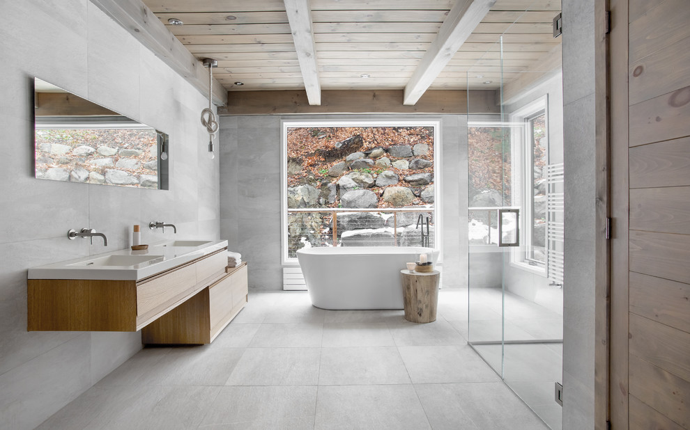Идея дизайна: главная ванная комната в современном стиле с плоскими фасадами, фасадами цвета дерева среднего тона, отдельно стоящей ванной, угловым душем, серой плиткой, монолитной раковиной, серым полом и открытым душем