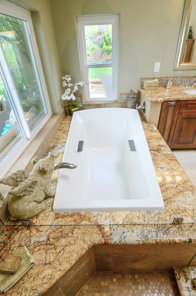 Design ideas for a large ensuite bathroom in Tampa with a submerged sink, raised-panel cabinets, brown cabinets, granite worktops, a built-in bath, a corner shower, a one-piece toilet, brown tiles, stone tiles, green walls and travertine flooring.