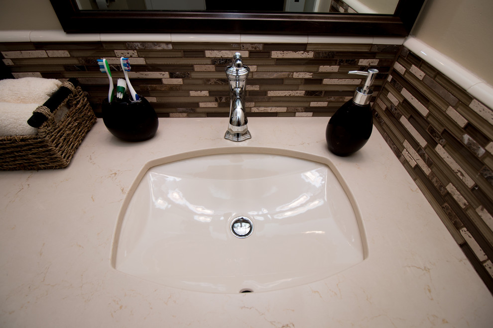 Aménagement d'une salle de bain principale classique en bois foncé de taille moyenne avec un placard à porte plane, WC séparés, un carrelage beige, un carrelage métro, un mur beige, un sol en vinyl, un lavabo encastré et un plan de toilette en quartz modifié.