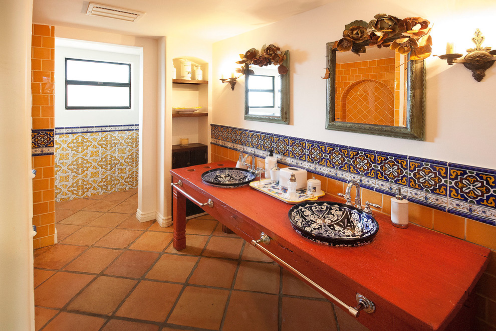 サンタバーバラにある地中海スタイルのおしゃれな浴室 (オーバーカウンターシンク、赤いキャビネット、マルチカラーのタイル) の写真