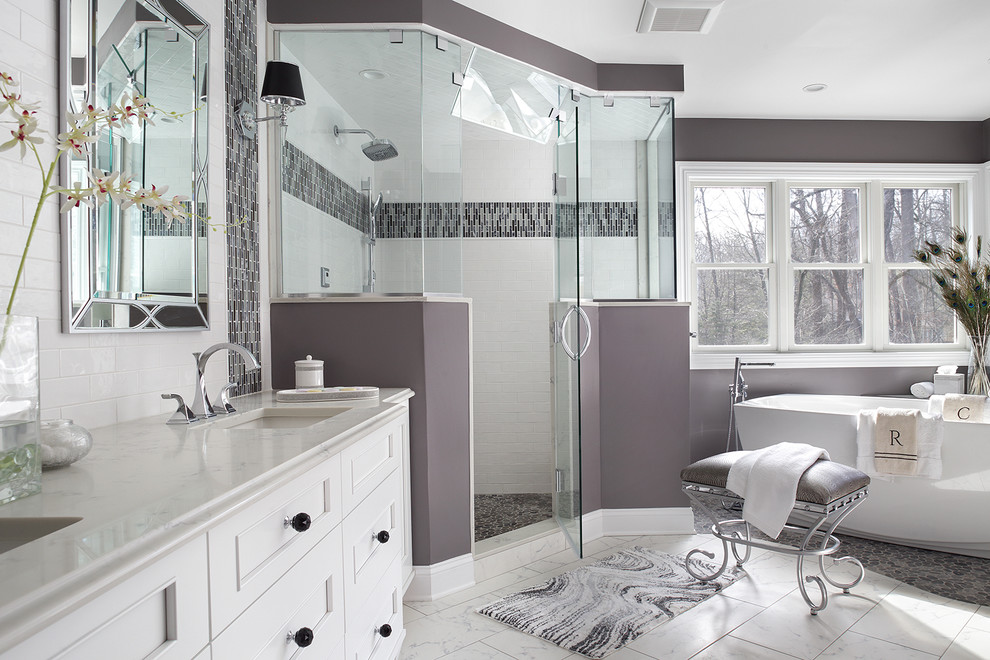 Пример оригинального дизайна: большая главная ванная комната в стиле неоклассика (современная классика) с фасадами с утопленной филенкой, белыми фасадами, отдельно стоящей ванной, угловым душем, унитазом-моноблоком, белой плиткой, стеклянной плиткой, фиолетовыми стенами, полом из керамогранита, врезной раковиной, столешницей из искусственного кварца, белым полом, душем с распашными дверями и белой столешницей