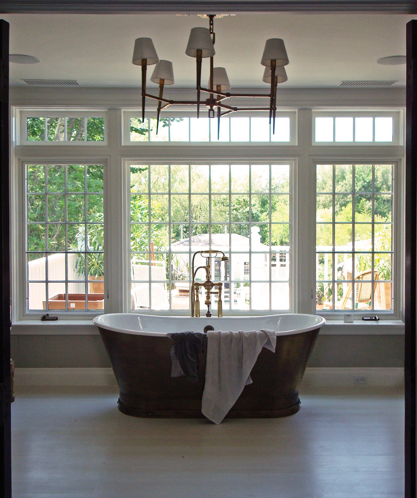 Ispirazione per una stanza da bagno padronale tradizionale con vasca freestanding, pareti bianche e parquet chiaro