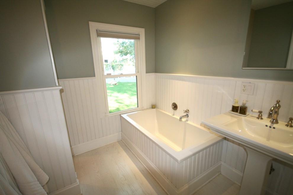 Klassisk inredning av ett en-suite badrum, med ett fristående badkar, en hörndusch, vit kakel, tunnelbanekakel, ett piedestal handfat, dusch med gångjärnsdörr, en toalettstol med separat cisternkåpa och beige väggar