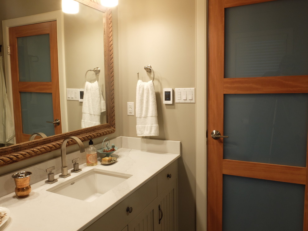 Foto på ett mellanstort vintage badrum med dusch, med vita skåp, en toalettstol med separat cisternkåpa, vita väggar, mörkt trägolv, ett undermonterad handfat, luckor med lamellpanel och bänkskiva i kvarts