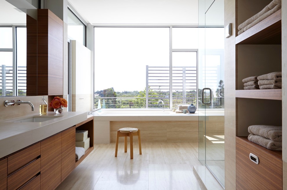 Cette image montre une grande salle de bain principale design en bois brun avec un placard à porte plane, une baignoire encastrée, une douche d'angle, un carrelage beige, parquet clair, un lavabo posé et un plan de toilette en marbre.