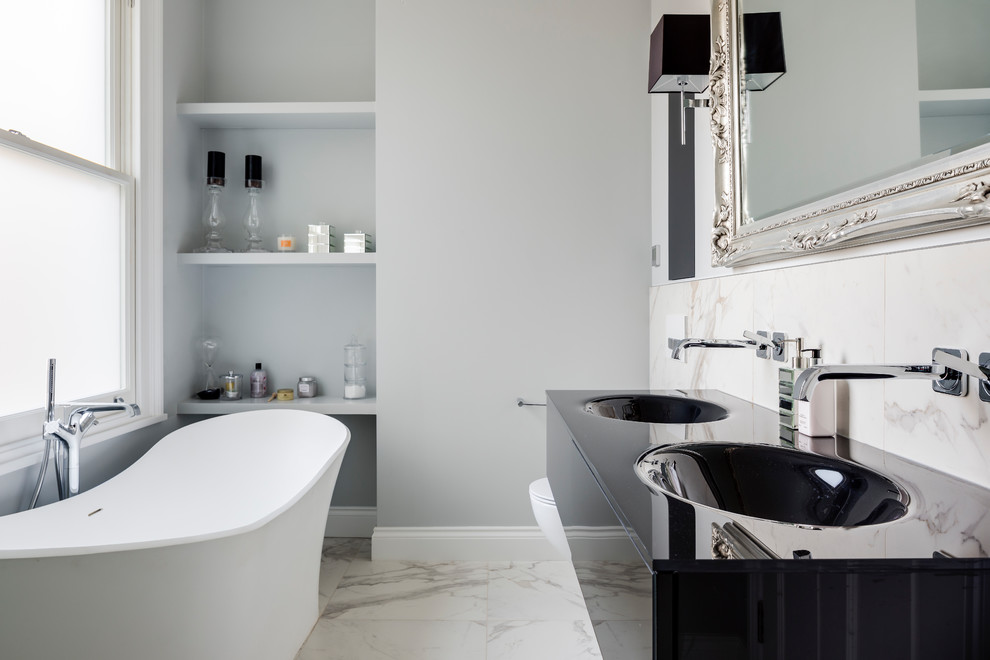 Immagine di una piccola stanza da bagno chic con nessun'anta, ante grigie, vasca freestanding, piastrelle di marmo, pareti grigie, pavimento in marmo, lavabo sospeso e pavimento bianco