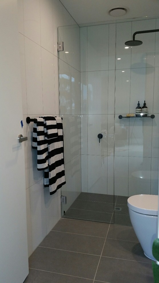 Foto på ett litet funkis en-suite badrum, med luckor med infälld panel, vita skåp, en kantlös dusch, en toalettstol med separat cisternkåpa, keramikplattor, vita väggar, klinkergolv i keramik och ett avlångt handfat