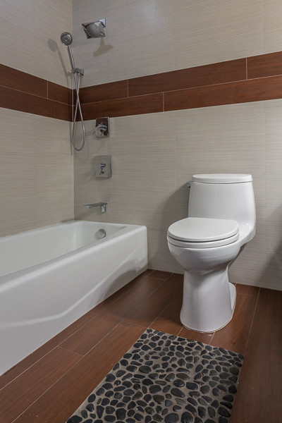 Kleines Retro Badezimmer mit Duschbadewanne, Toilette mit Aufsatzspülkasten, braunen Fliesen und Fliesen in Holzoptik in Miami