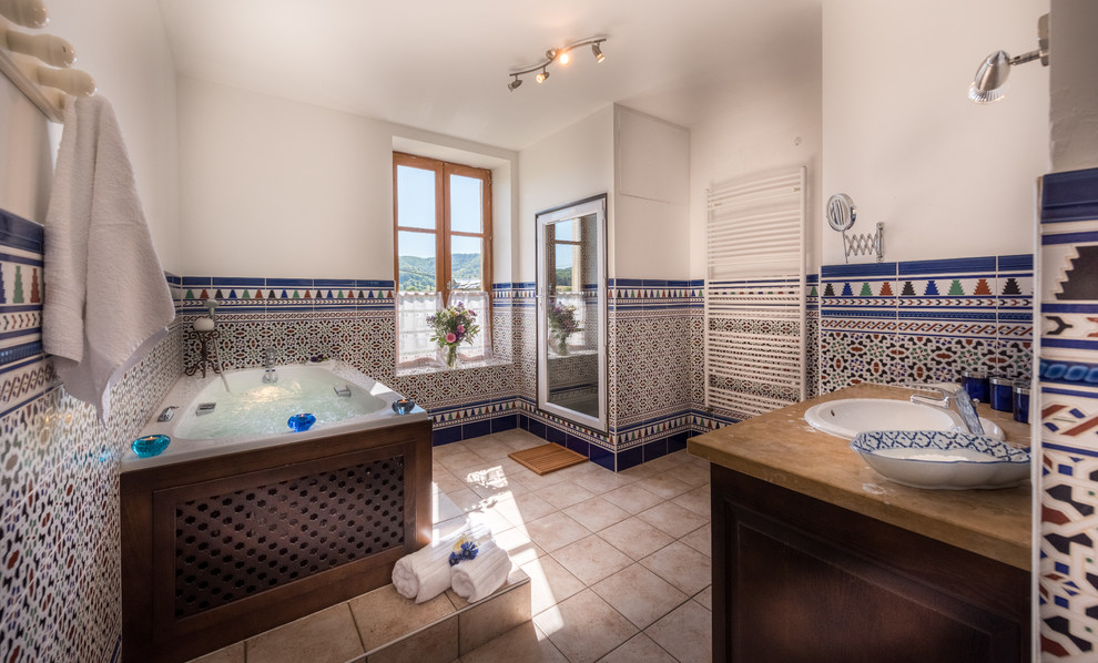 Réalisation d'une salle de bain principale méditerranéenne en bois foncé de taille moyenne avec un bain bouillonnant, un espace douche bain, WC séparés, un carrelage beige, mosaïque, un mur blanc, un lavabo intégré, un plan de toilette en marbre et une cabine de douche à porte battante.